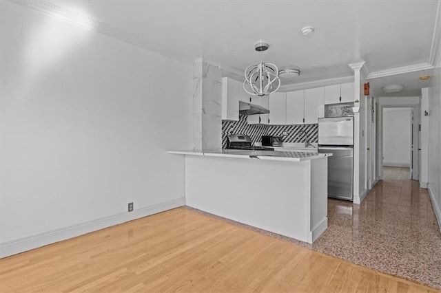 kitchen featuring tasteful backsplash, white cabinets, freestanding refrigerator, a peninsula, and ornamental molding