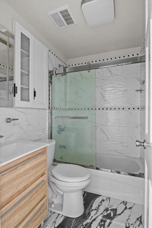 full bath with visible vents, vanity, marble finish floor, toilet, and bath / shower combo with glass door