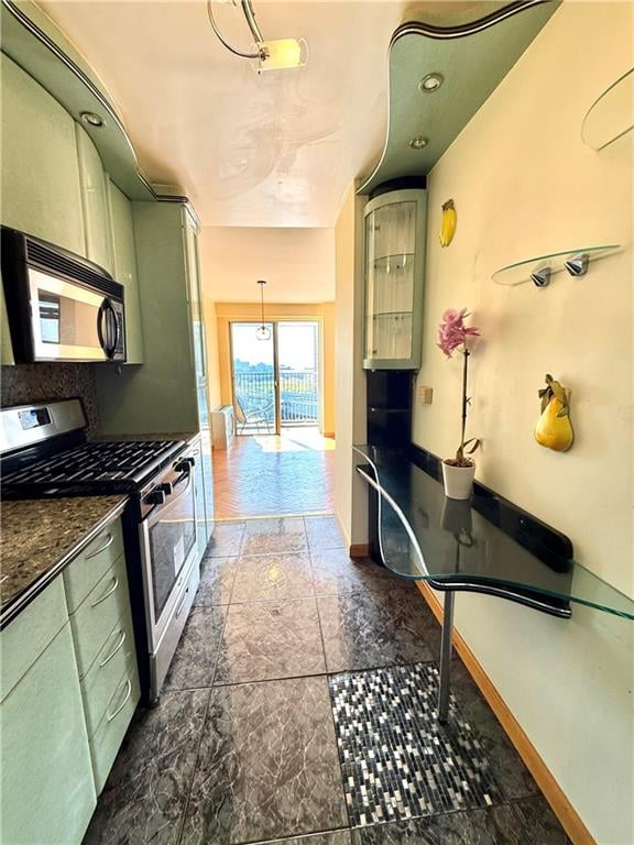kitchen featuring dark countertops, appliances with stainless steel finishes, baseboards, and green cabinets