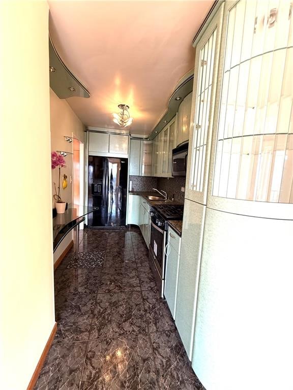 kitchen with dark countertops, appliances with stainless steel finishes, decorative backsplash, and a sink