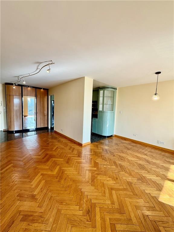 spare room with baseboards and rail lighting