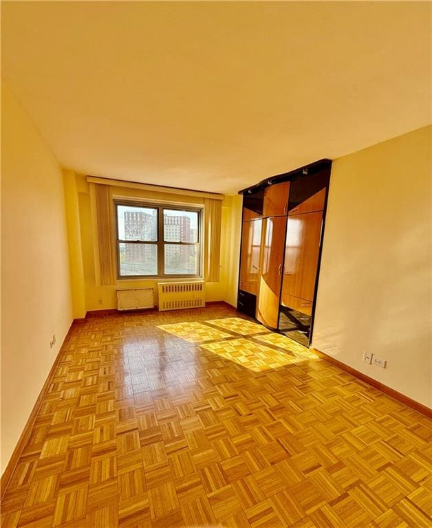 spare room featuring baseboards and radiator