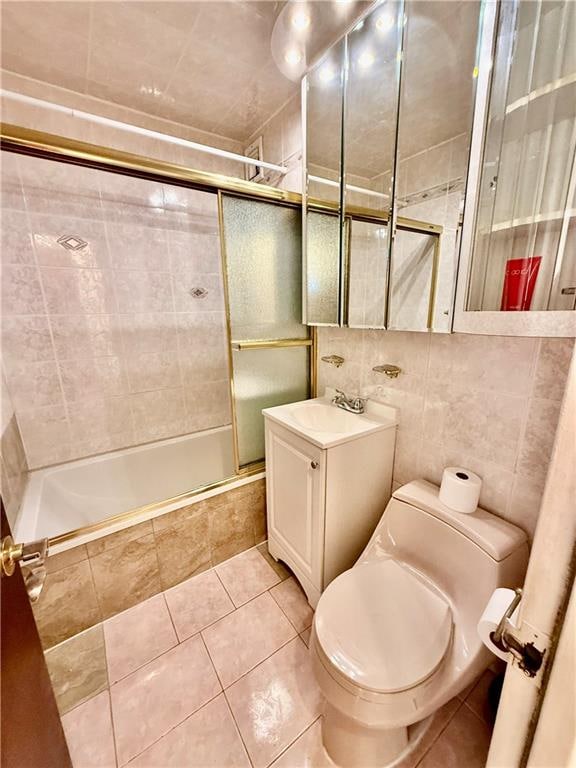 bathroom with vanity, toilet, tile walls, tiled shower / bath, and tile patterned floors