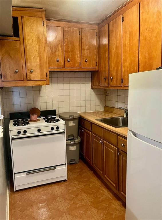 kitchen with white appliances, brown cabinets, a sink, and light countertops