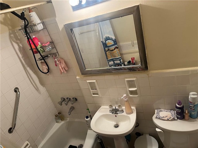 bathroom with shower / bath combination with curtain, toilet, tile walls, a wainscoted wall, and a sink