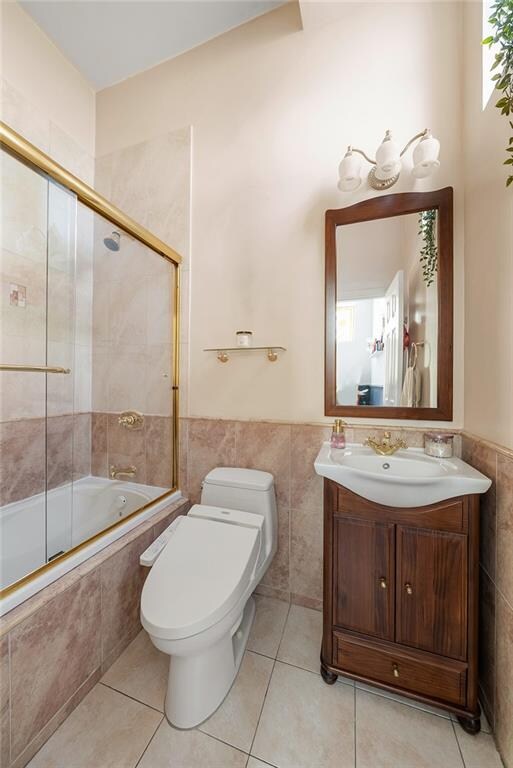 bathroom featuring tile walls, tiled shower / bath, toilet, and tile patterned floors