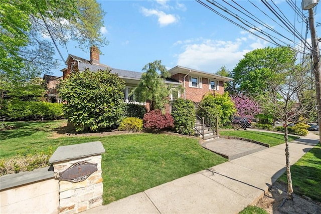 view of front of home featuring brick siding, a front lawn, and a chimney
