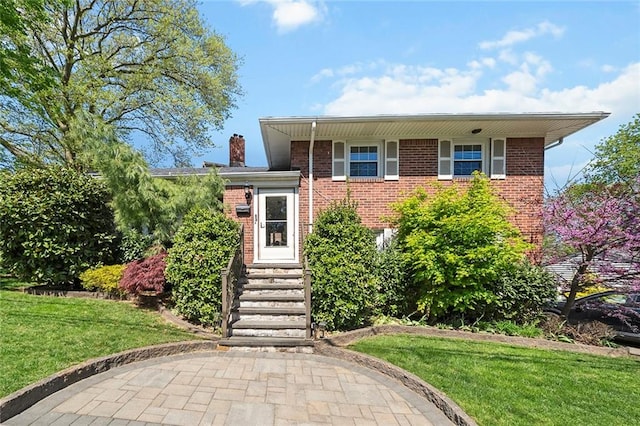 tri-level home with brick siding, a front yard, a chimney, and entry steps