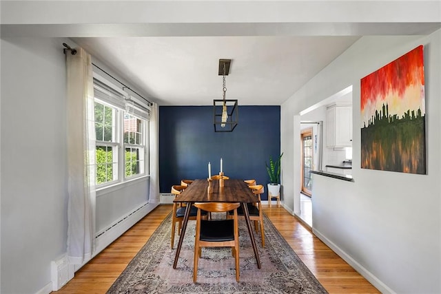 dining room with baseboards, a baseboard heating unit, and light wood-style floors