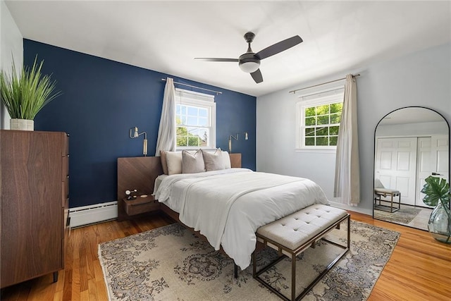 bedroom featuring a ceiling fan, wood finished floors, and a baseboard radiator
