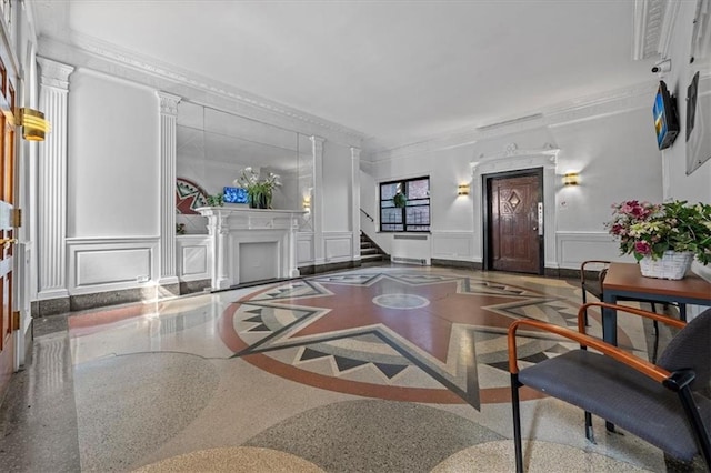 living area featuring ornamental molding, a wainscoted wall, stairway, and a decorative wall