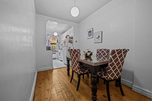 dining area with arched walkways, baseboards, and hardwood / wood-style floors