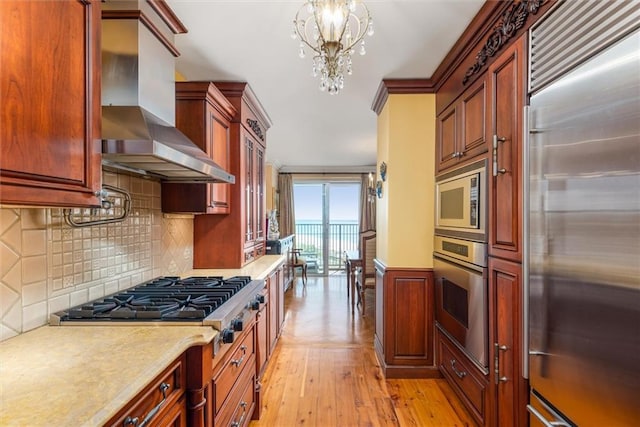 501 Surf Ave Unit 16K, Brooklyn, NY 11224 - kitchen featuring built in appliances, light wood-type flooring, ventilation hood, a chandelier, and light countertops