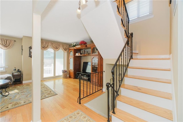 stairs with wood finished floors and a wealth of natural light