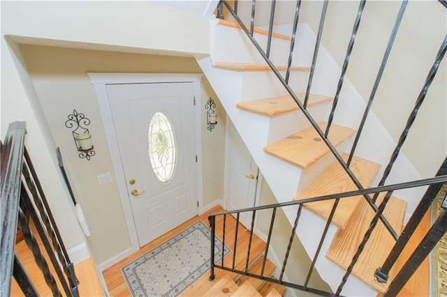 foyer with stairway, baseboards, and wood finished floors
