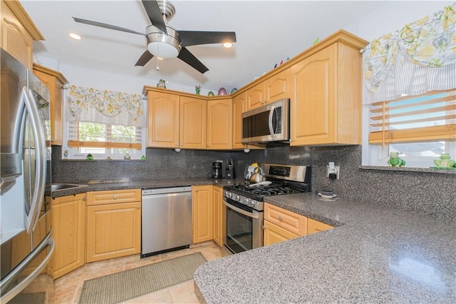 kitchen with light brown cabinets, a ceiling fan, stainless steel appliances, and backsplash