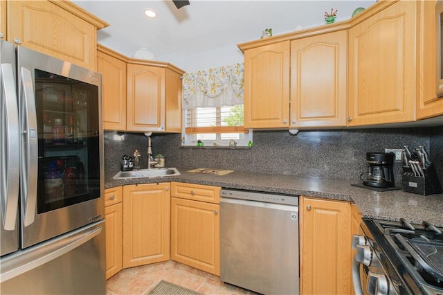 kitchen featuring decorative backsplash, dark countertops, a sink, light brown cabinets, and stainless steel appliances