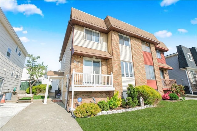 townhome / multi-family property featuring a shingled roof, a front yard, and brick siding