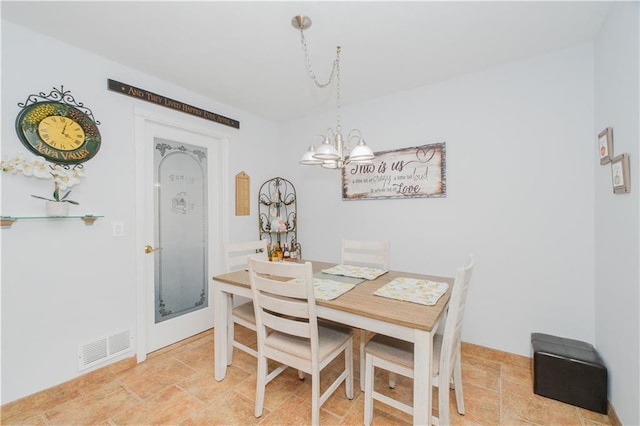 dining space featuring visible vents, stone finish flooring, and a chandelier