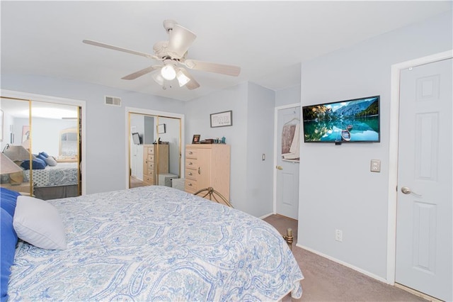 carpeted bedroom with baseboards, a ceiling fan, two closets, and visible vents