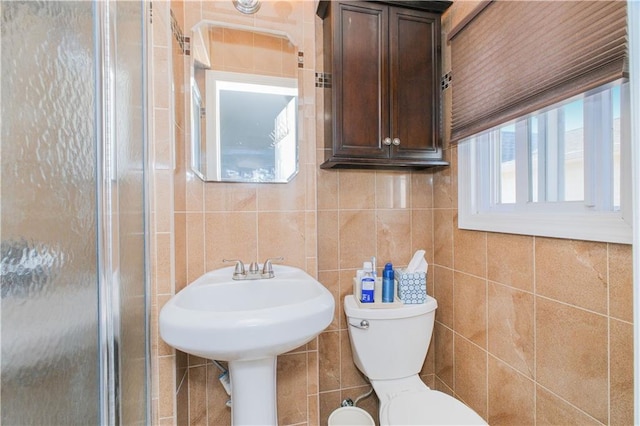 bathroom featuring tile walls, a healthy amount of sunlight, toilet, and a shower stall
