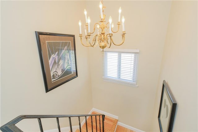 staircase featuring baseboards and a chandelier