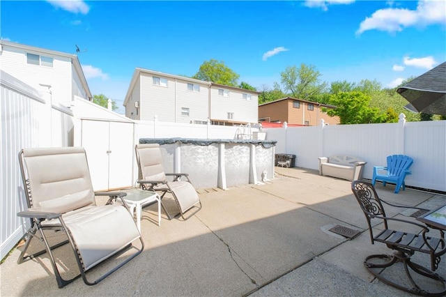 view of patio with a fenced in pool, a fenced backyard, and a storage unit
