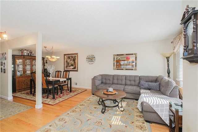 living area featuring baseboards, light wood-type flooring, and a notable chandelier