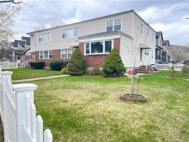 view of front of property with brick siding, a front lawn, and fence