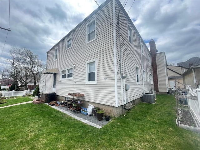 rear view of house featuring fence, a yard, and cooling unit