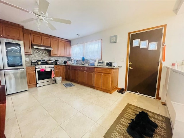 kitchen featuring decorative backsplash, light countertops, under cabinet range hood, light tile patterned floors, and stainless steel appliances