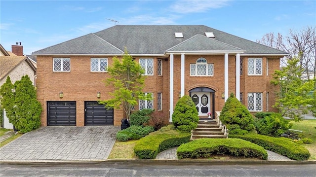 greek revival house with brick siding, decorative driveway, and a garage