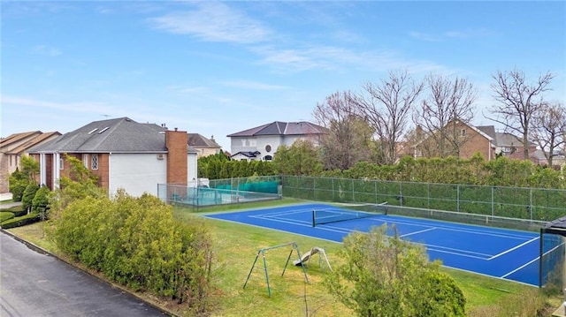 view of tennis court featuring a residential view and fence