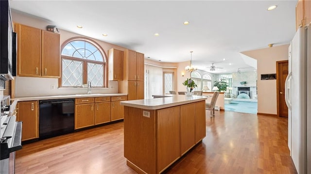 kitchen with a kitchen island, light countertops, a sink, light wood-style flooring, and dishwasher
