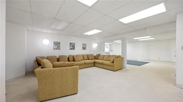 living area featuring a paneled ceiling and baseboards