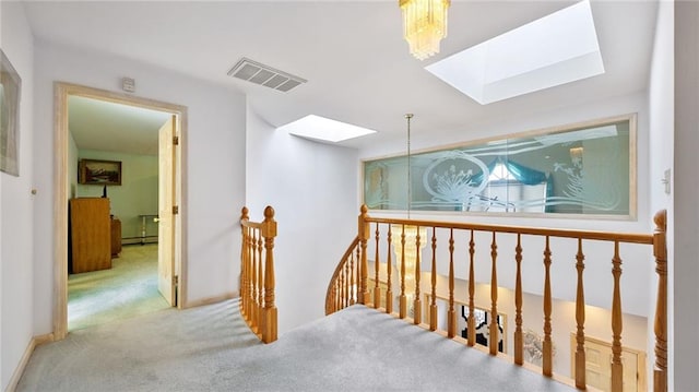 hall with baseboards, carpet flooring, visible vents, an upstairs landing, and a skylight