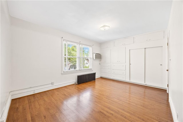 1933 E 28th St, Brooklyn, NY 11229 - unfurnished bedroom with radiator heating unit, light wood-style floors, a wall mounted air conditioner, baseboards, and a closet