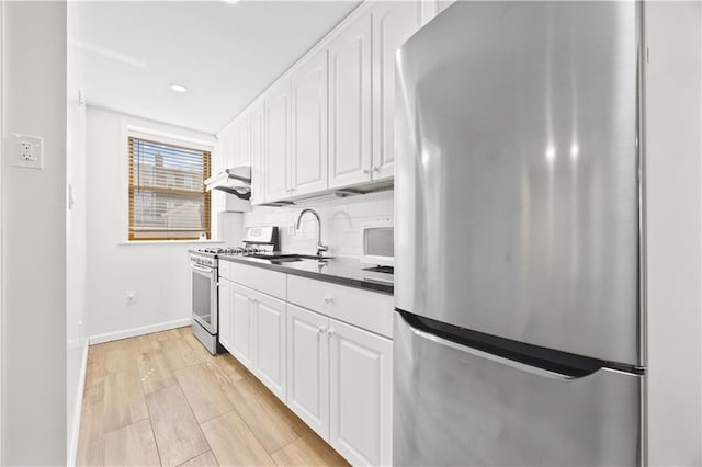 1933 E 28th St, Brooklyn, NY 11229 - kitchen featuring appliances with stainless steel finishes, under cabinet range hood, dark countertops, white cabinets, and recessed lighting