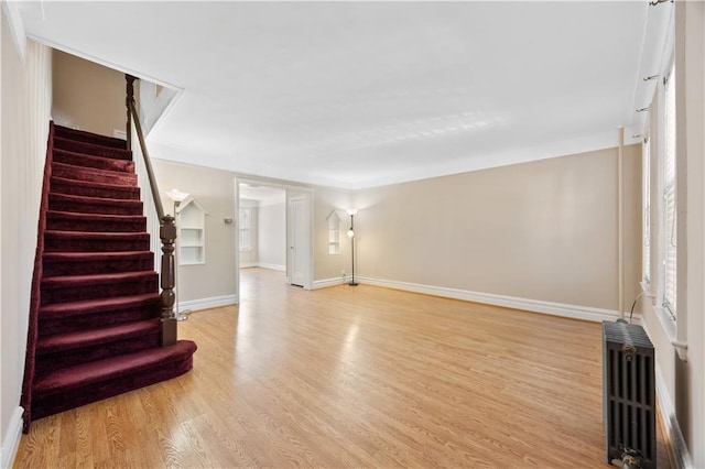 1933 E 28th St, Brooklyn, NY 11229 - unfurnished living room with radiator heating unit, light wood-style flooring, baseboards, and stairs