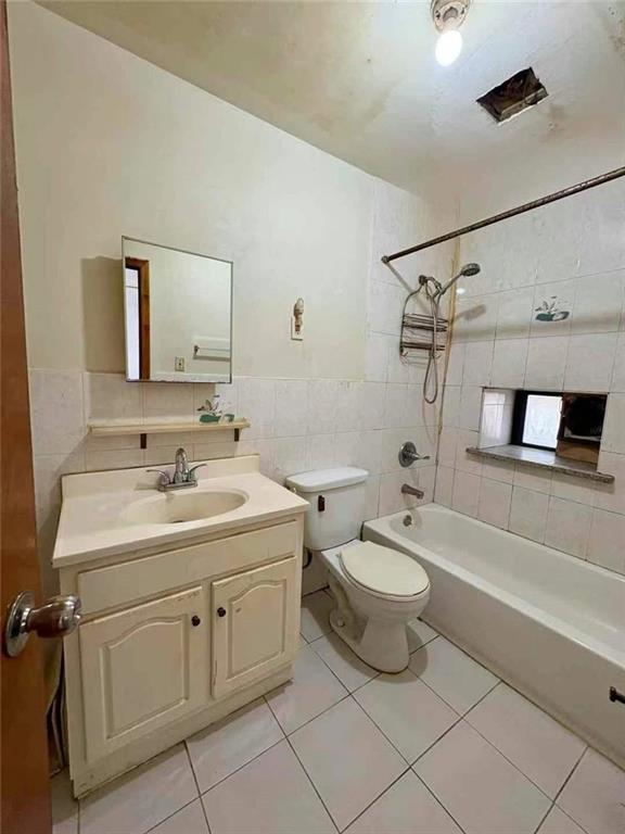 full bathroom with toilet, washtub / shower combination, tile walls, tile patterned flooring, and vanity