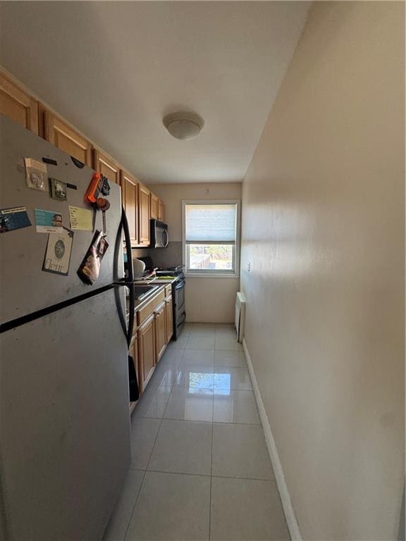 kitchen with stainless steel appliances, light tile patterned floors, brown cabinets, and baseboards