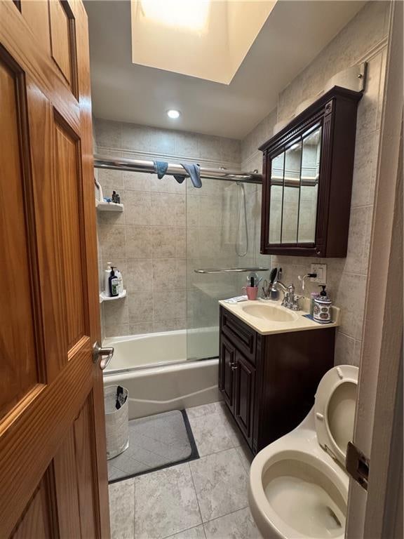 bathroom with toilet, vanity, and bath / shower combo with glass door
