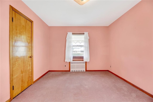 carpeted empty room with baseboards and radiator heating unit