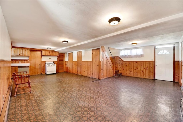 bonus room with dark floors, wood walls, a wainscoted wall, and stairway