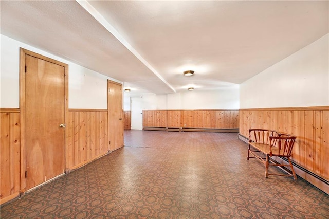interior space featuring a baseboard radiator, wood walls, and wainscoting