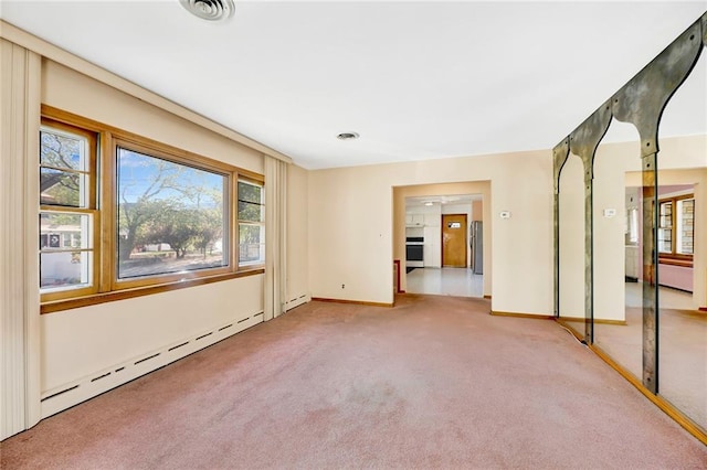 unfurnished room with a baseboard heating unit, baseboards, visible vents, and carpet floors