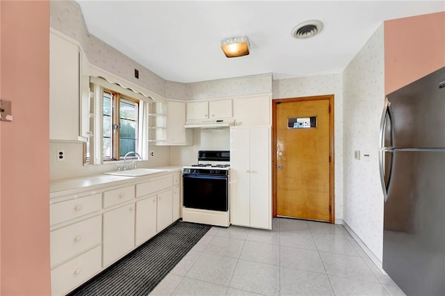 kitchen with a sink, freestanding refrigerator, gas range gas stove, and wallpapered walls