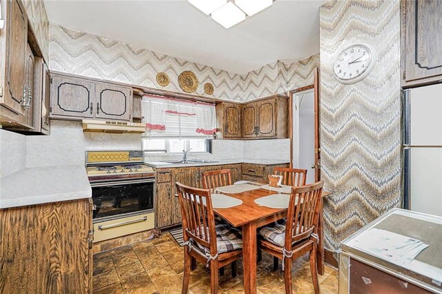 222 Albemarle Rd, Brooklyn, NY 11218 - kitchen with range with gas cooktop, a sink, under cabinet range hood, wallpapered walls, and light countertops