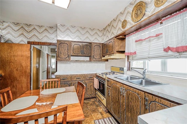 222 Albemarle Rd, Brooklyn, NY 11218 - kitchen featuring gas range oven, a sink, under cabinet range hood, light countertops, and wallpapered walls