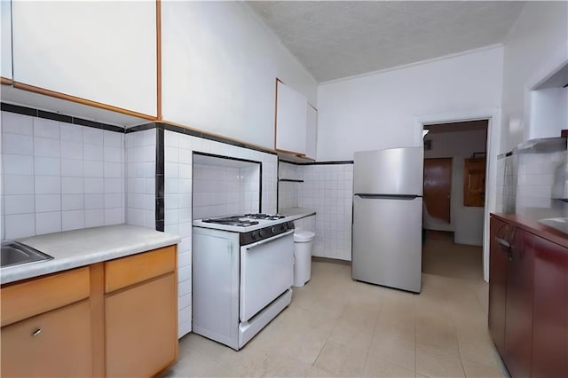 94 Wyona St, Brooklyn, NY 11207 - kitchen featuring freestanding refrigerator, gas range gas stove, tile walls, light countertops, and a wainscoted wall
